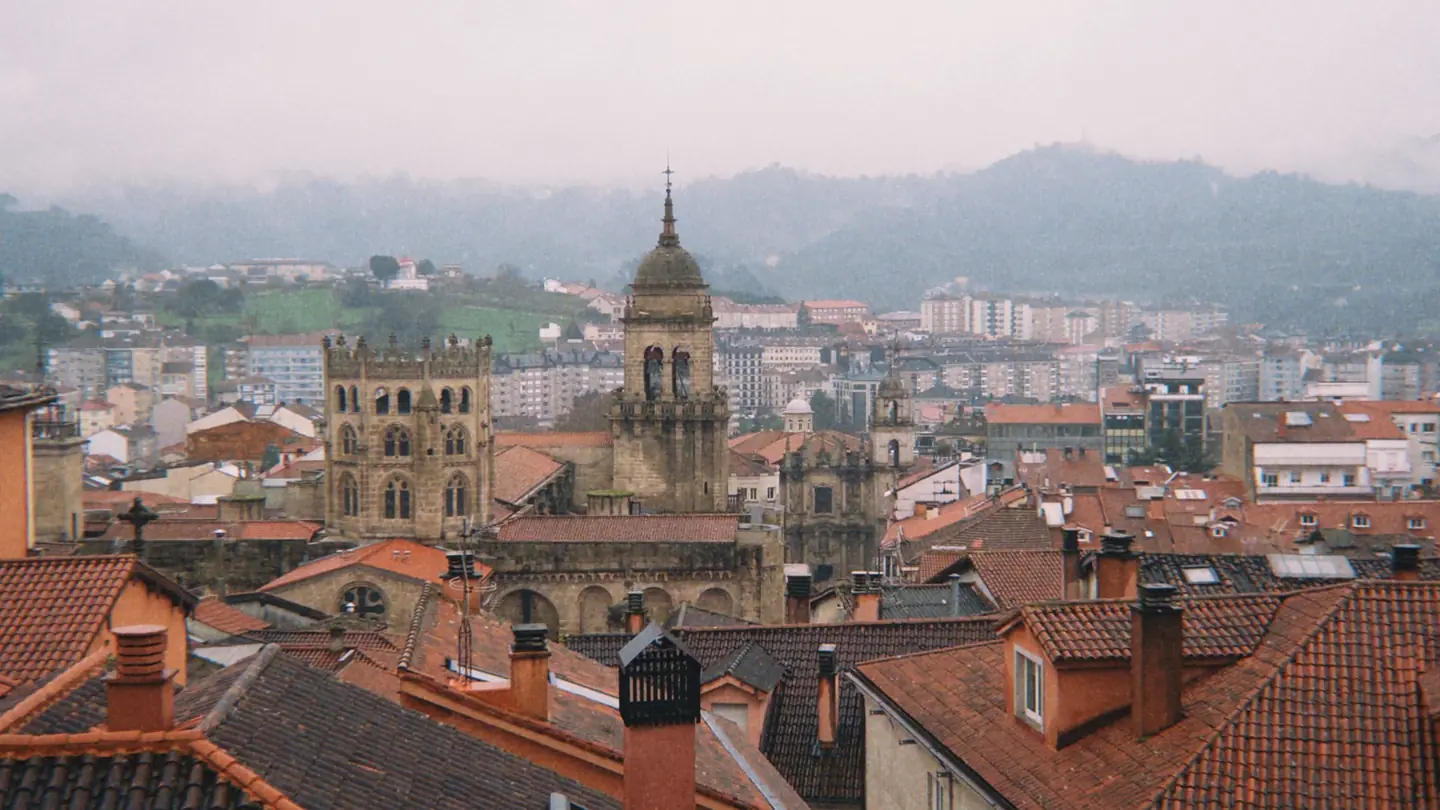Tejados del casco histórico de Oviedo con la torre de la catedral y los montes al fondo